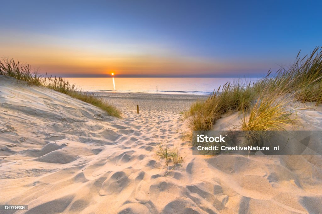Sunset View over ocean from dune in Zeeland Inviting Sunset View over ocean from dune over North Sea and Canal in Ouddorp, Zeeland Province, the Netherlands. Outdoor scene of coast in nature of Europe. Beach Stock Photo