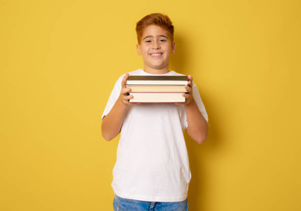 istock Happy little boy with books isolated on yellow background 1347776613