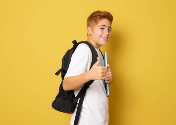 istock Happy school boy with thumb up isolated over yellow background. 1347776705