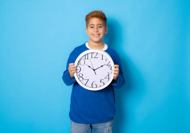 istock Portrait of caucasian boy with clock. Education and time concept. 1347777421