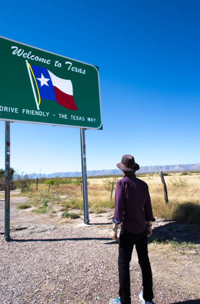istock Texas Road Sign: Man Reading Welcome to Texas Sign 1347780896