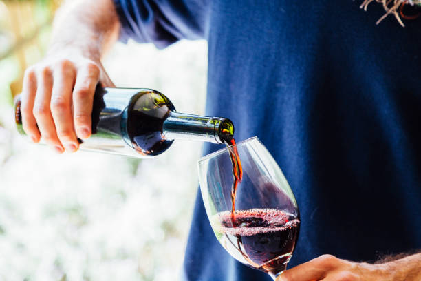 istock A young man with a bottle pouring wine into a glass. 1347782910