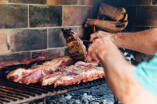 reifer mann beim grillen. er stößt das fleisch mit einer gabel an. - steak argentina food silverware stock-fotos und bilder