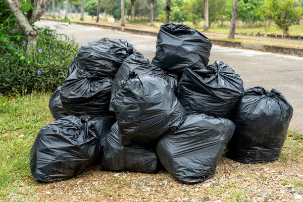 schwarze müllsäcke auf der straße mit grünem gras und pflanzenhintergrund - garbage stock-fotos und bilder