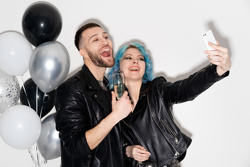 Birthday selfie. Happy couple. Party celebration. Catch moments. Stylish cheerful man and woman making photo on smartphone with balloons decoration isolated white.