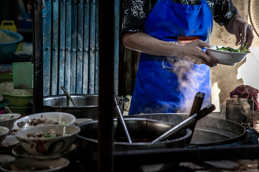Bangkok, Thailand - 27 Oct 2019 : Chef cooking egg Noodles with roasted pork in local restaurant, Thailand street food. making noodle in Traditional Asian Food. Chinese egg noodle and hot boiled soup, Selective focus.