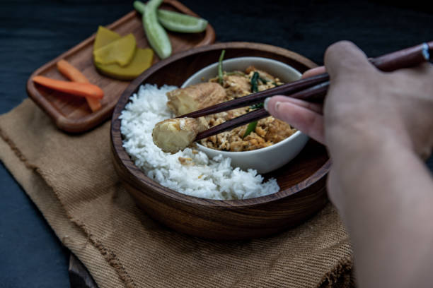 istock The hand is using chopsticks to pick up  Stir fried egg tofu with spring onion with Herbs vegetables served with steamed rice in wooden bowl. 1347789005