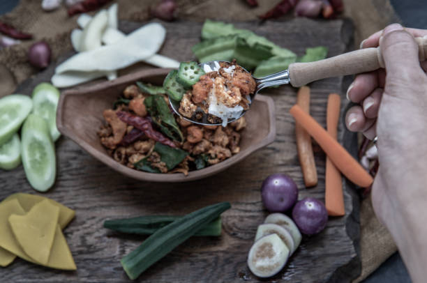 istock The hand is using a spoon to scoop Pork Crackling Chili Paste with fried kaffir lime leaves with the ingredient and fresh vegetables on wood background. 1347789013