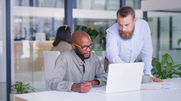 istock Shot of two businessmen using a laptop in a modern office 1347789194