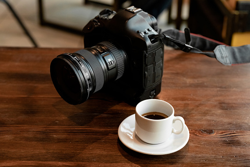 Professional digital camera with coffee on wooden table