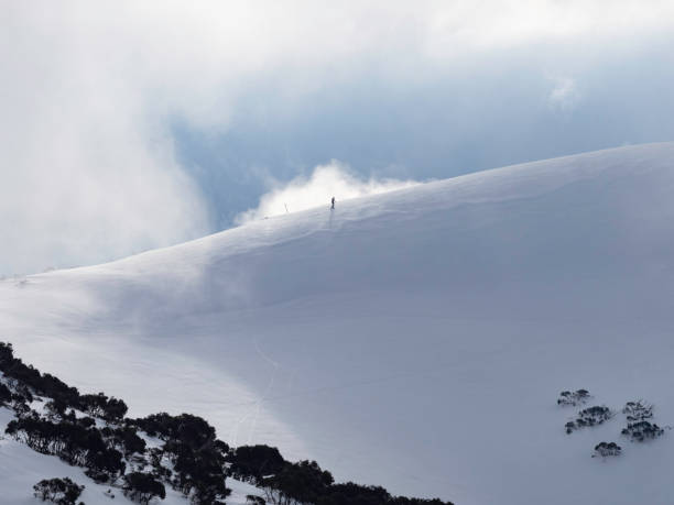 Snowshoeing on mountain ridgeline Distant people on snowy ridgeline snowshoeing up at Mt Hotham in the Australian Alps high country stock pictures, royalty-free photos & images