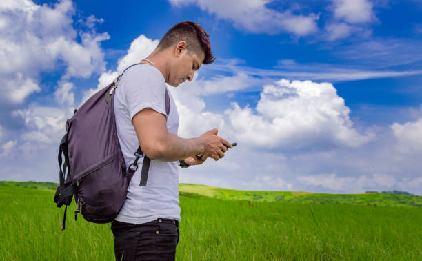 istock Man calling by cell phone, young man in the field calling by cell phone, young backpacker with cell phone in the field and copy space 1347795809