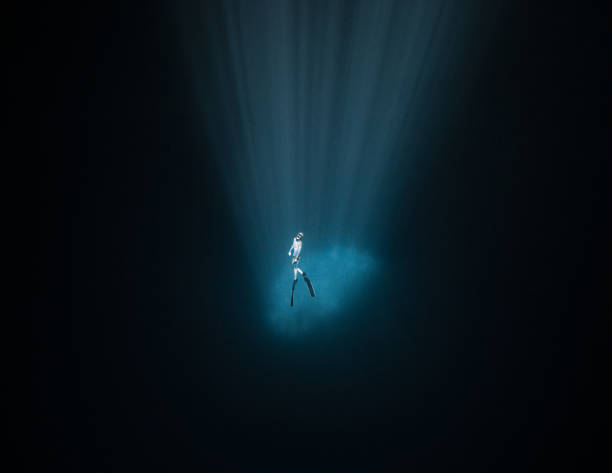 Freediver inside the light of a Cenote at 30 meters deep