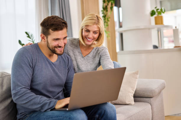 istock Young couple using a laptop while relaxing on the sofa at home 1347800501