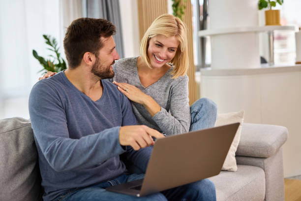 istock Young couple using a laptop while relaxing on the sofa at home 1347800551