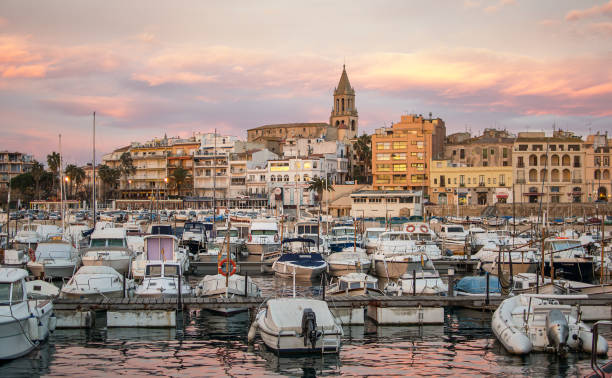 Sunset in Palamós, Girona, Costa Brava Sunset with the golden sky of the town of Palamós in Girona, Costa Brava, with its characteristic bell tower and the boats that are moored in the port landscape arch photos stock pictures, royalty-free photos & images