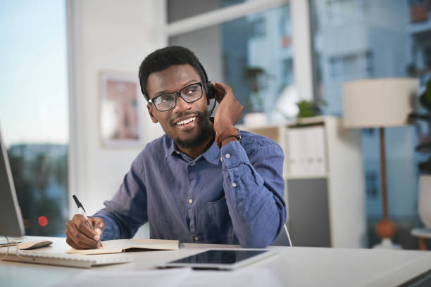 istock Shot of a young man using a computer and headset in a modern office 1347814891