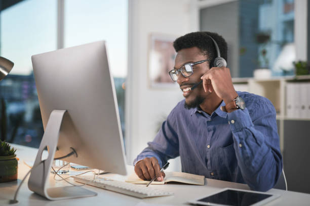 istock Shot of a young man using a computer and headset in a modern office 1347814893