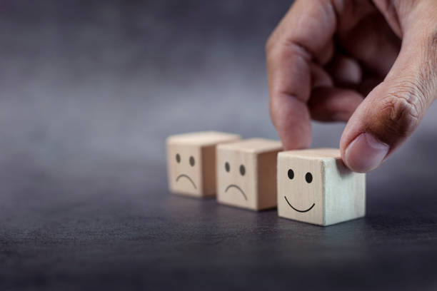 istock Close up customer hand choose smiley face and blurred sad face on wood cube 1347816015