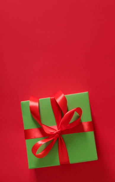 istock gift box green on red background with red bow with place for text 1347817005