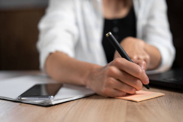 istock Business lady taking notes while working in the office. Woman's hand with a pen close-up. The manager is writing something handwritten at the table. Business and work. 1347818728