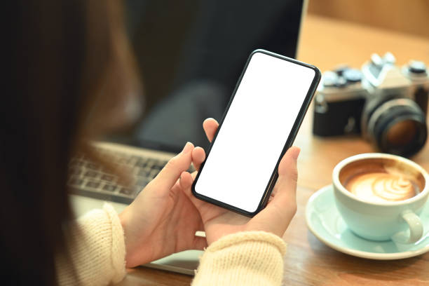 istock View over shoulder young woman holding smart phone with empty display. 1347818789
