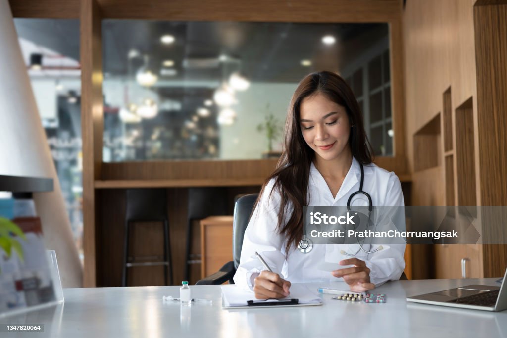 Beautiful female doctor wearing uniform filling medical documents. 20-24 Years Stock Photo