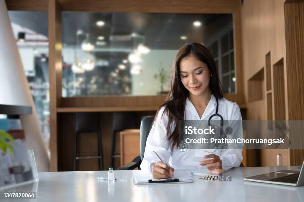 Beautiful Female Doctor Wearing Uniform Filling Medical Documents Stock Photo - Download Image Now