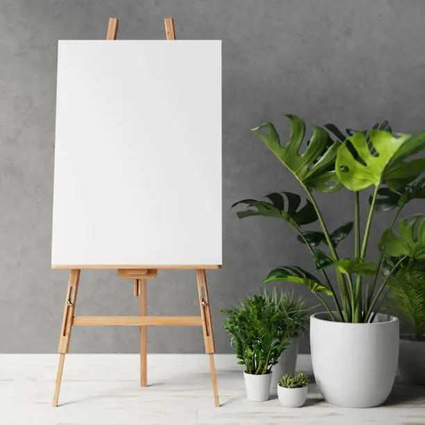 Blank canvas on wooden easel with plant