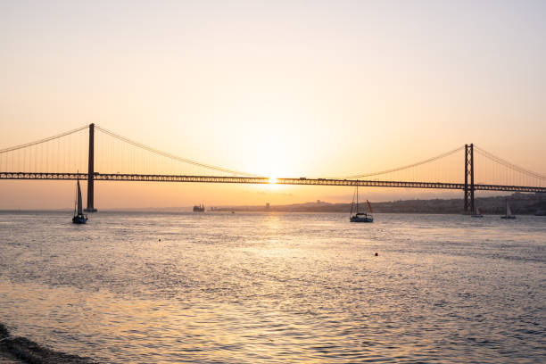 istock Sunset in a river with a bridge and a sailing boat 1347822251