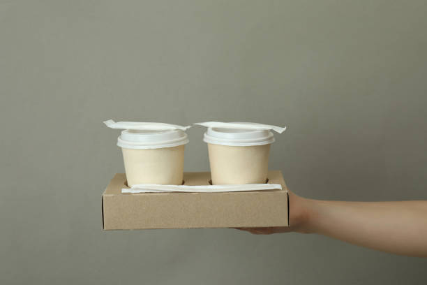 istock Female hand hold paper cups on gray background 1347830170