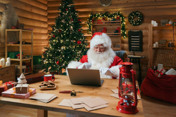 istock Santa Claus in a christmasy hut, working on a laptop 1347831481