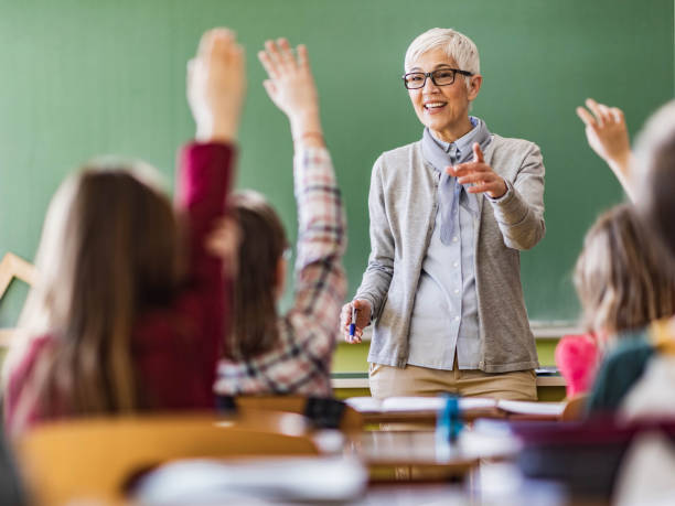 istock Happy senior teacher giving a lecture at elementary school. 1347832395