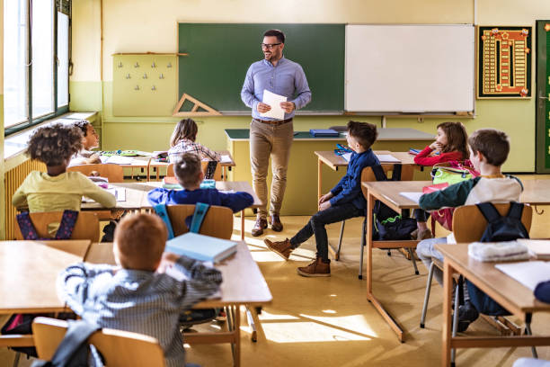 istock Happy male teacher giving a lecture at elementary school. 1347832447