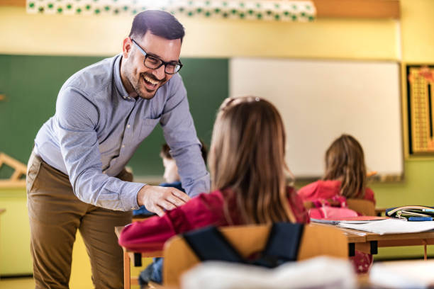 istock Young happy professor assisting his elementary students on a class at school. 1347832471