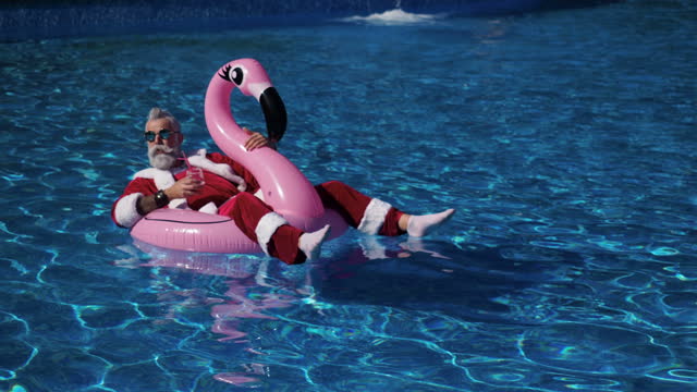 Santa floating in inflatable ring in swimming pool