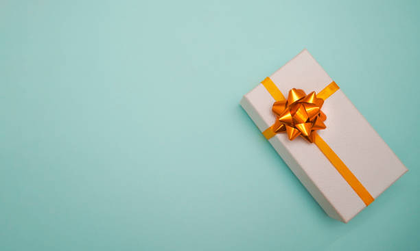 istock White gift box with golden bow on pastel blue background. Banner with copy space. Christmas, New Year, Birthday, shopping sales concept. 1347836082
