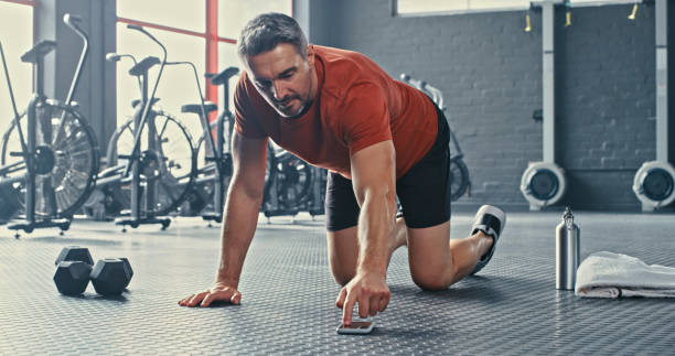 istock Shot of a mature man selecting music from his cellphone before doing mountain climbers during his workout 1347836427