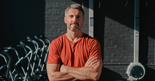 Shot of a handsome mature man standing with his arms folded after his workout in the gym Don’t limit your challenges. Challenge your limits gym men africa muscular build stock pictures, royalty-free photos & images