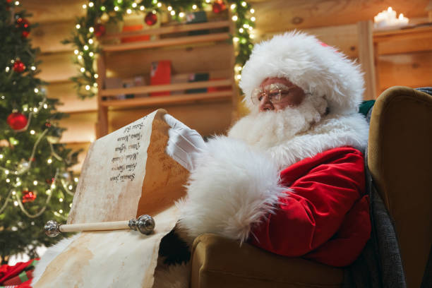 Santa Claus is sitting in a chair with a long paper scroll in his hands Santa Claus in a warm fur coat made of white sheep's fur is sitting In a chair , holding an old paper scroll tightly with both hands and reading it carefully. animator photos stock pictures, royalty-free photos & images
