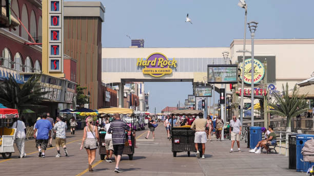 Atlantic City, United States- June 5, 2014: People are walking along the boardwalk in Atlantic City, New Jersey.  Atlantic City is a seaside resort city in the northeastern United States. It is famously known for it's boardwalk, beach, casinos and hotels.  It is also the home of the Miss America Pageant.  Bally's Hotel and Casino is shown in this picture.  The boardwalk has several piers and attractions. Visitors can buy their famous saltwater taffy and fudge.  There are many souvenir and gift shops to shop at.