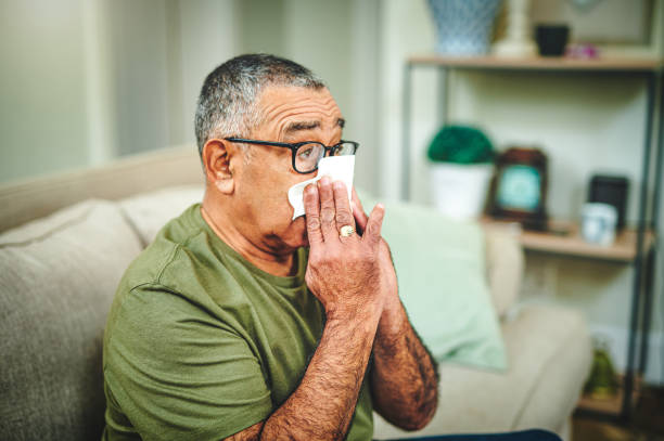 집에서 티슈로 코를 불고 있는 노인의 총 - man flu 뉴스 사진 이미지