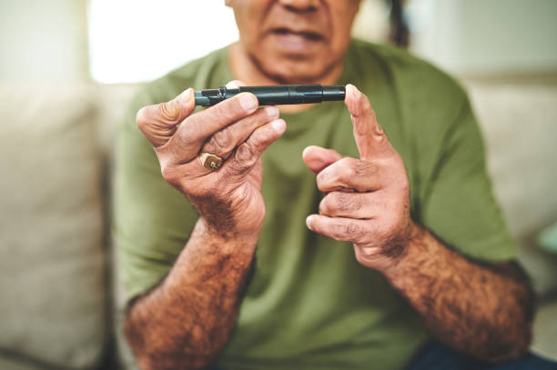 foto de un hombre mayor que usa un dispositivo de pinchazo en el dedo para controlar sus niveles de azúcar en la sangre - diabetes blood illness chronic fotografías e imágenes de stock