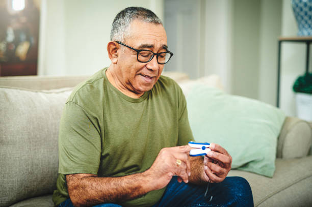 Shot of a senior man using a pulse oximeter at home Everyone needs one of these pulse oxymeter stock pictures, royalty-free photos & images