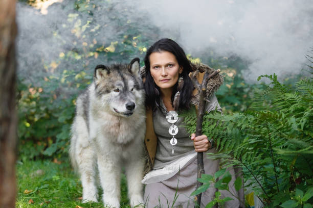 Forest dweller woman with a large dog Alaskan Malamute in the forest Portrait of a forest dweller young woman with a large dog Alaskan Malamute in the autumn forest malamute stock pictures, royalty-free photos & images