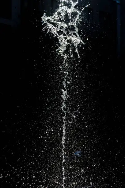 Water splashing from a fountain against a black background