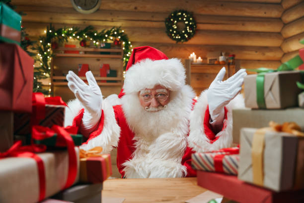 Santa Claus is  inviting us, by the gesture of his hands Santa Claus is  inviting us, by the gesture of his hands, we see  him in a centre of the photo  in the Christmas interior with a lot of presents in the foreground animator photos stock pictures, royalty-free photos & images