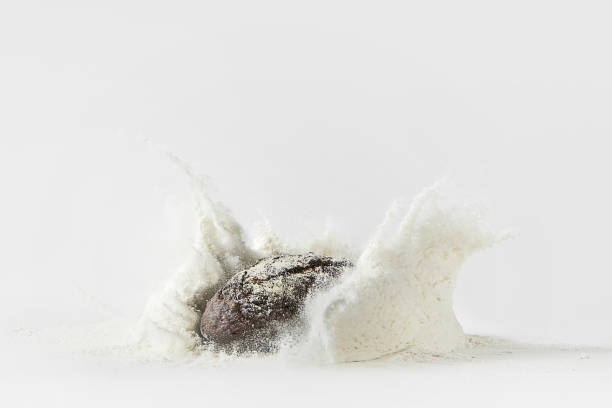 istock Minimalistic picture - rye bread falling into flour on a white background 1347851112