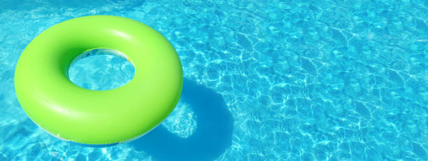 istock Bright inflatable ring floating in swimming pool on sunny day, space for text. Banner design 1347853344