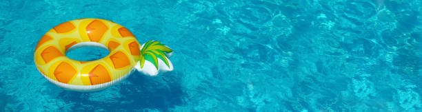 istock Bright inflatable pineapple ring floating in swimming pool on sunny day, space for text. Banner design 1347853406